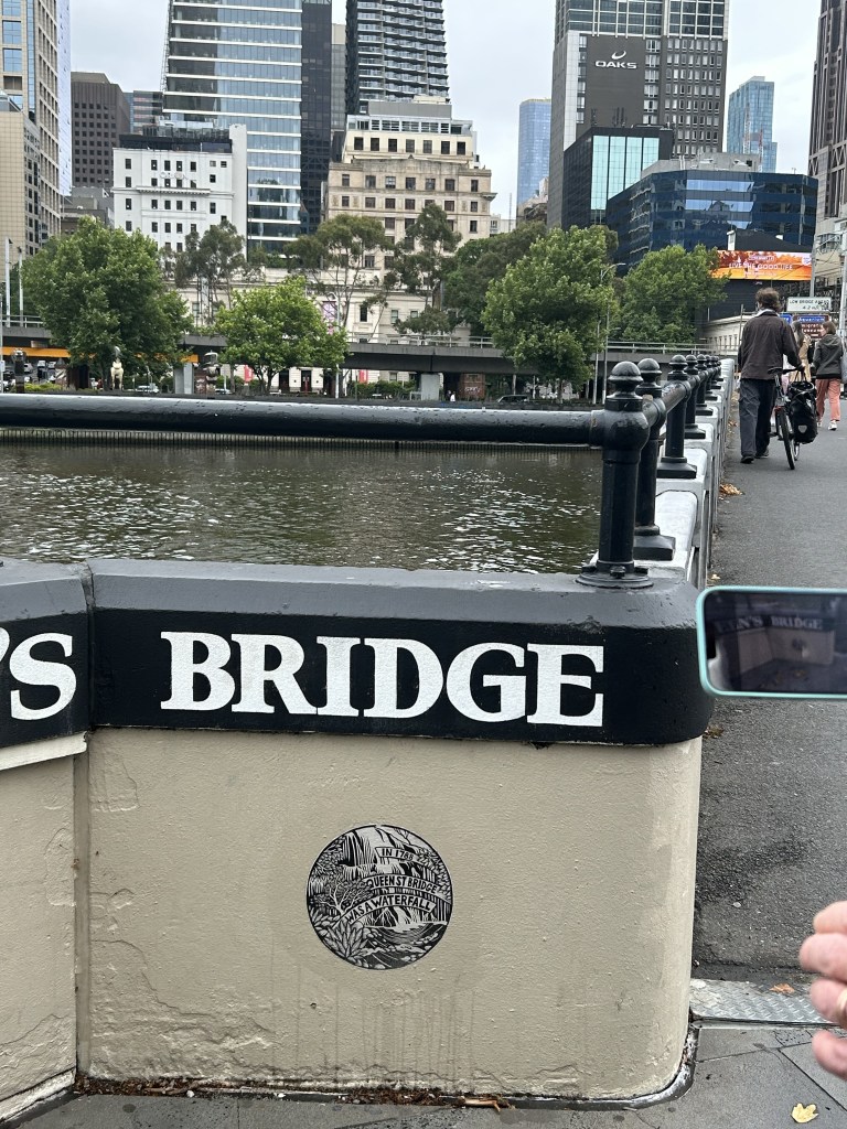 A picture of a wall beside a river with a sticker on it that says "In 1788 queen street bridge was a waterfall"